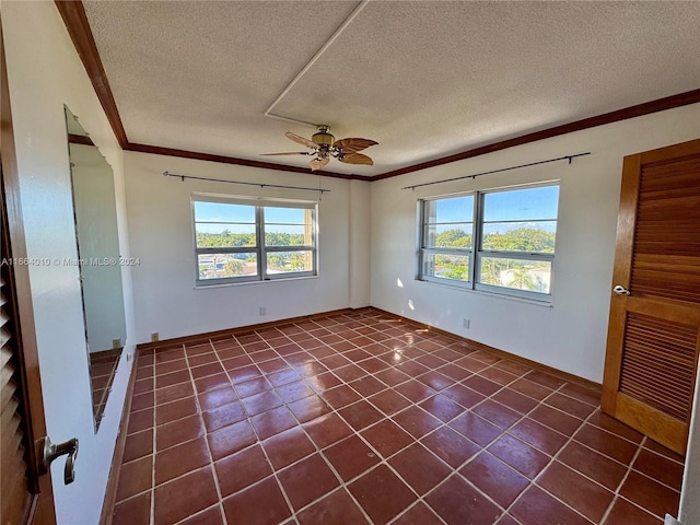 unfurnished room featuring ceiling fan, dark tile patterned floors, a textured ceiling, and ornamental molding