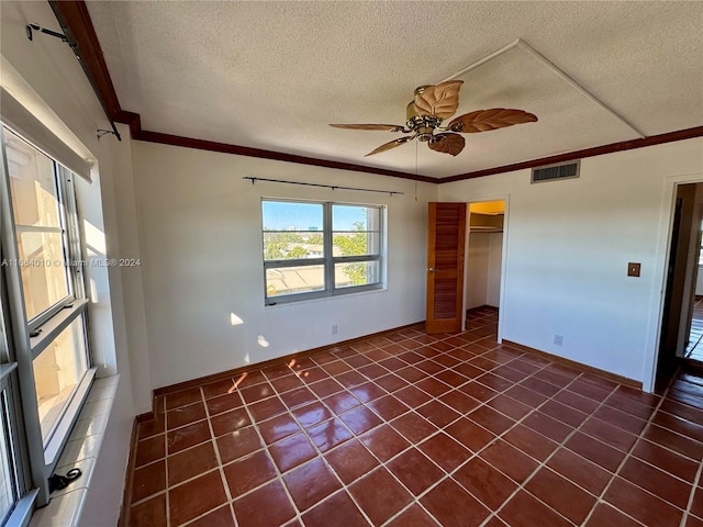 unfurnished bedroom with ceiling fan, crown molding, a textured ceiling, a closet, and dark tile patterned flooring