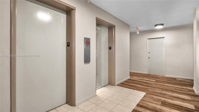 hall featuring elevator and light tile patterned floors