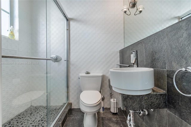 bathroom with toilet, an enclosed shower, tile walls, and sink