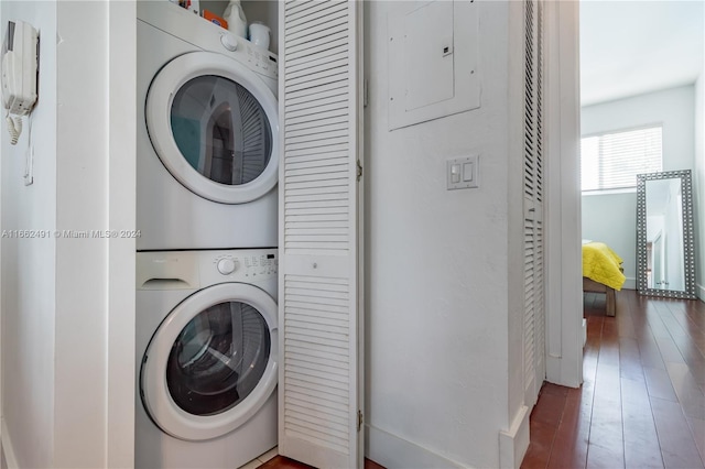 laundry room featuring dark wood-type flooring, electric panel, and stacked washer and dryer