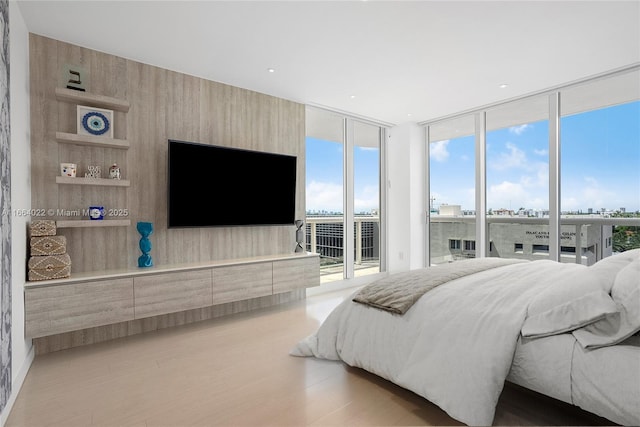 bedroom featuring access to exterior, expansive windows, and light wood finished floors