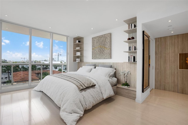 bedroom featuring light wood finished floors, a wall of windows, and recessed lighting