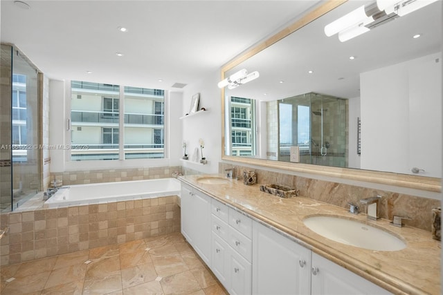 bathroom featuring a garden tub, a sink, a shower stall, and double vanity