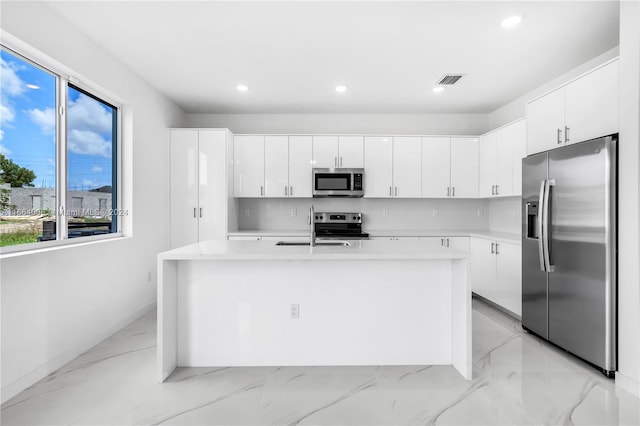 kitchen featuring stainless steel appliances, white cabinetry, a kitchen island with sink, and sink