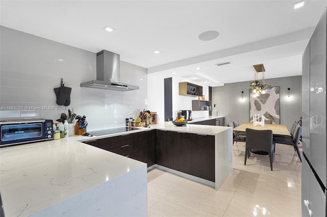 kitchen with light stone counters, kitchen peninsula, wall chimney exhaust hood, decorative light fixtures, and black electric cooktop