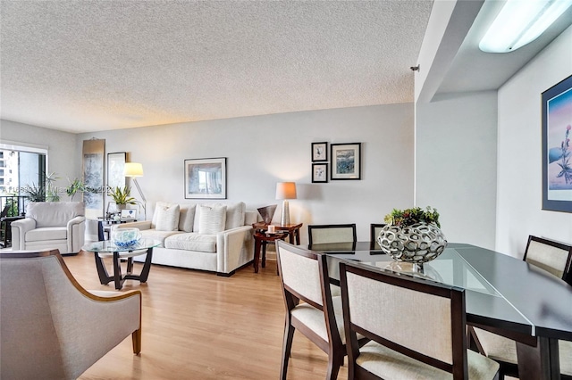 dining area featuring light wood-type flooring and a textured ceiling