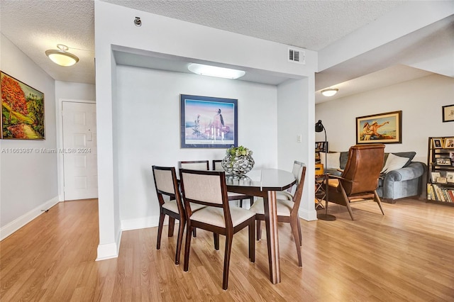 dining space with a textured ceiling and light hardwood / wood-style floors