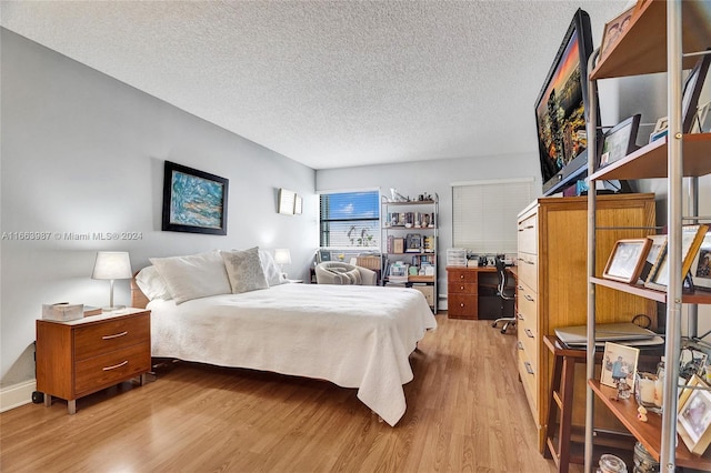 bedroom with a textured ceiling and light hardwood / wood-style flooring