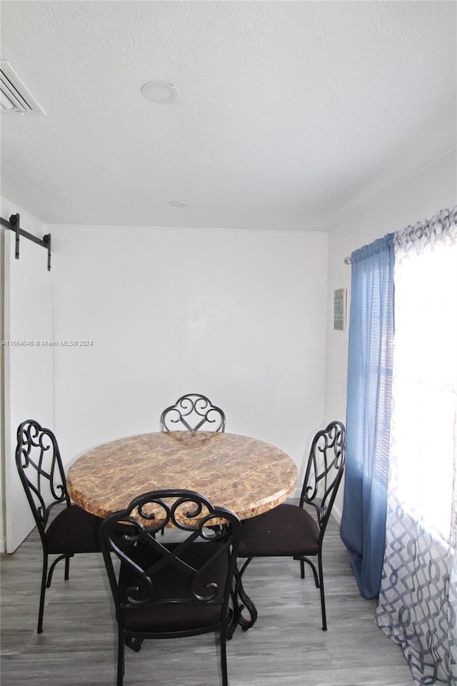 dining space featuring a textured ceiling, hardwood / wood-style floors, and a barn door