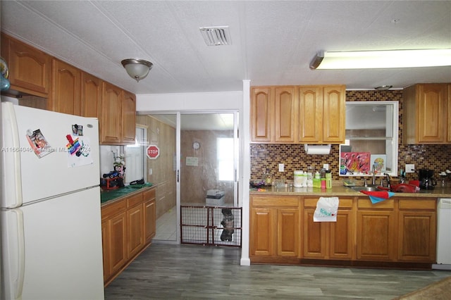 kitchen featuring backsplash, white appliances, sink, and dark wood-type flooring