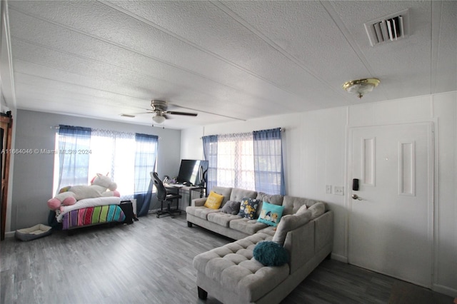 living room with a textured ceiling, dark wood-type flooring, and ceiling fan