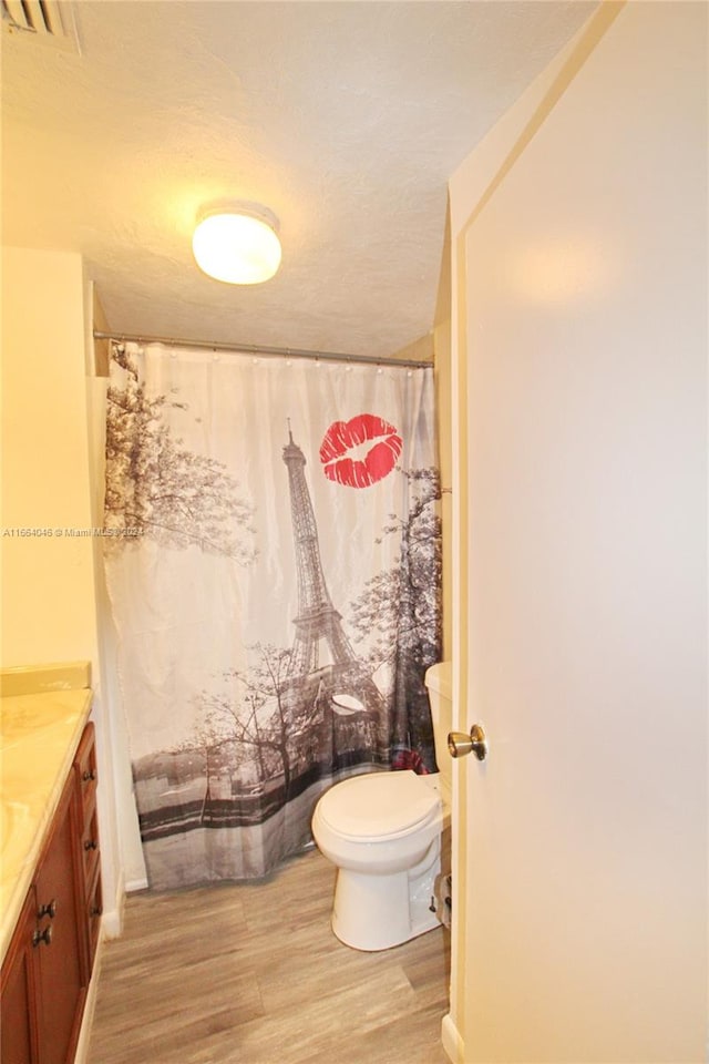 bathroom with a textured ceiling, hardwood / wood-style flooring, vanity, and toilet