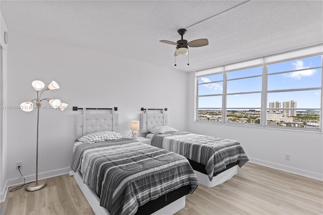 bedroom with light wood-type flooring, ceiling fan, and a textured ceiling