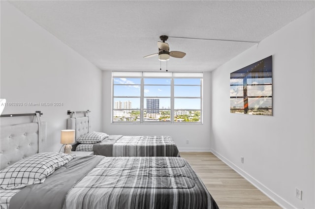 bedroom featuring ceiling fan, a textured ceiling, and light hardwood / wood-style flooring