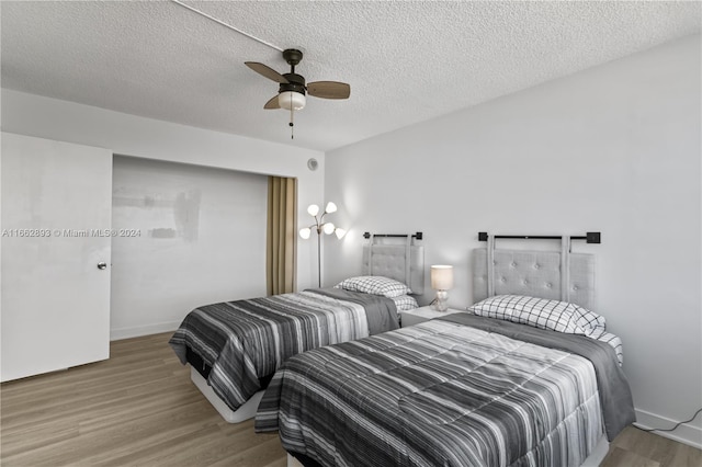 bedroom with ceiling fan, hardwood / wood-style flooring, and a textured ceiling