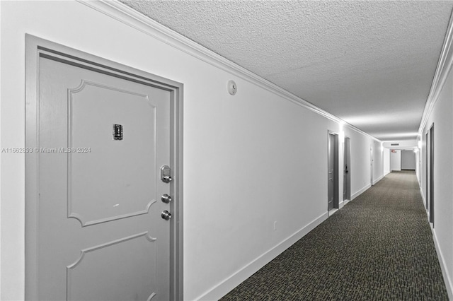 hall featuring ornamental molding, dark carpet, and a textured ceiling