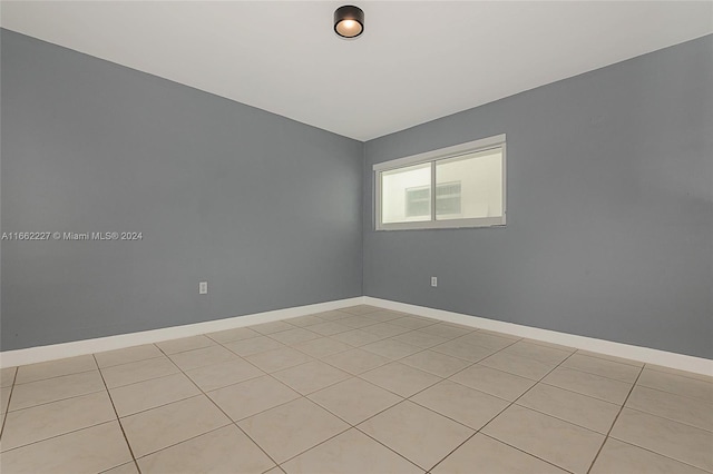 empty room featuring lofted ceiling and light tile patterned flooring