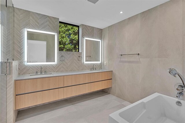 bathroom with vanity, tile walls, and a bath