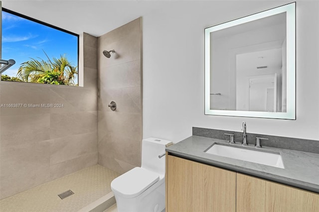 bathroom with tiled shower, vanity, and toilet