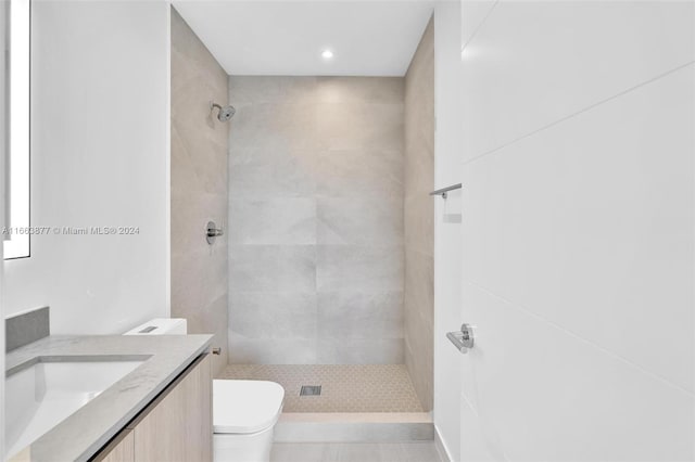 bathroom with a tile shower, vanity, and toilet