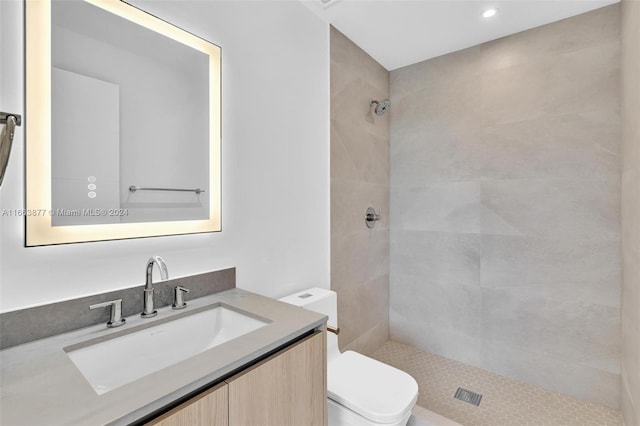 bathroom featuring a tile shower, vanity, and toilet