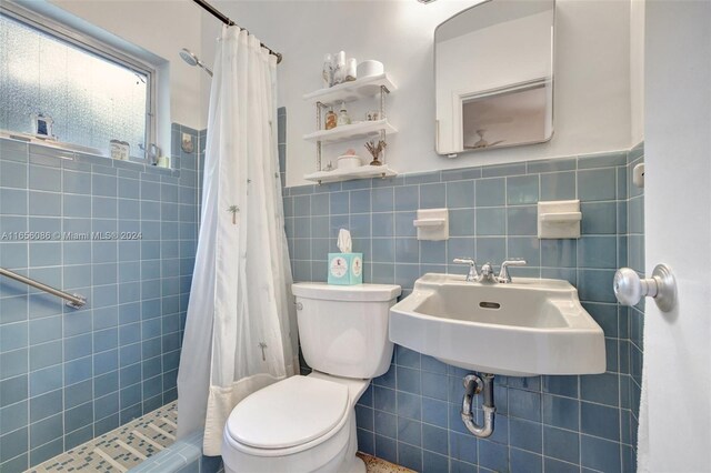 bathroom featuring a shower with curtain, sink, tile walls, and toilet