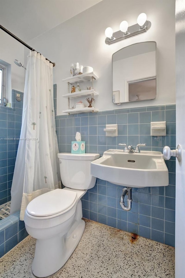 bathroom with walk in shower, tile walls, toilet, and sink