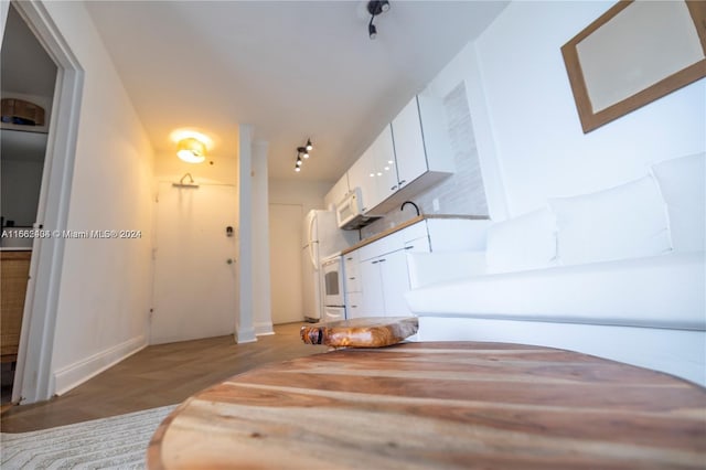 interior space featuring white cabinets, light wood-type flooring, and white appliances