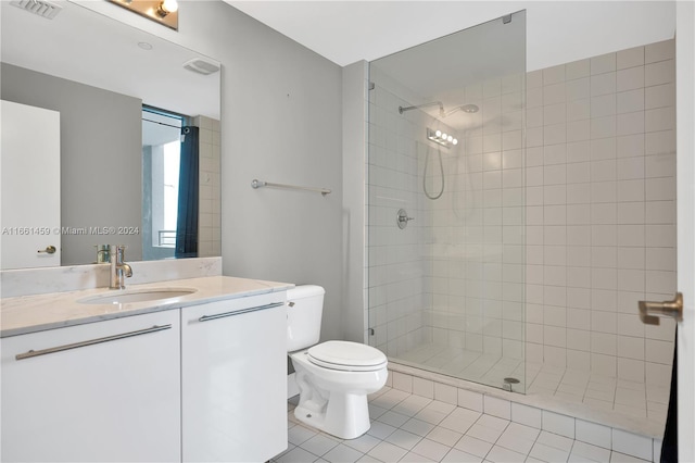 bathroom featuring toilet, vanity, tiled shower, and tile patterned floors