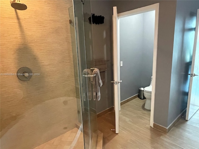 bathroom featuring walk in shower, hardwood / wood-style flooring, and toilet