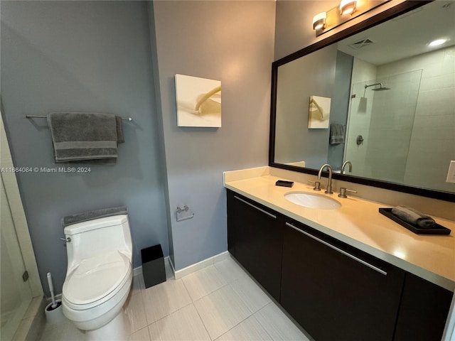 bathroom with tiled shower, vanity, toilet, and tile patterned floors