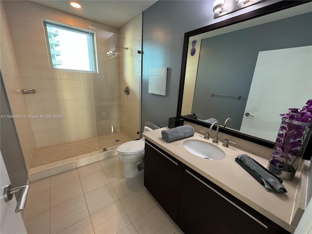 bathroom featuring a tile shower, tile patterned flooring, vanity, and toilet