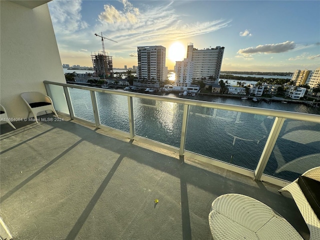 balcony at dusk featuring a water view