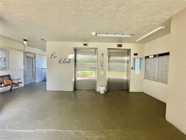 interior space with a textured ceiling, a mail area, and elevator