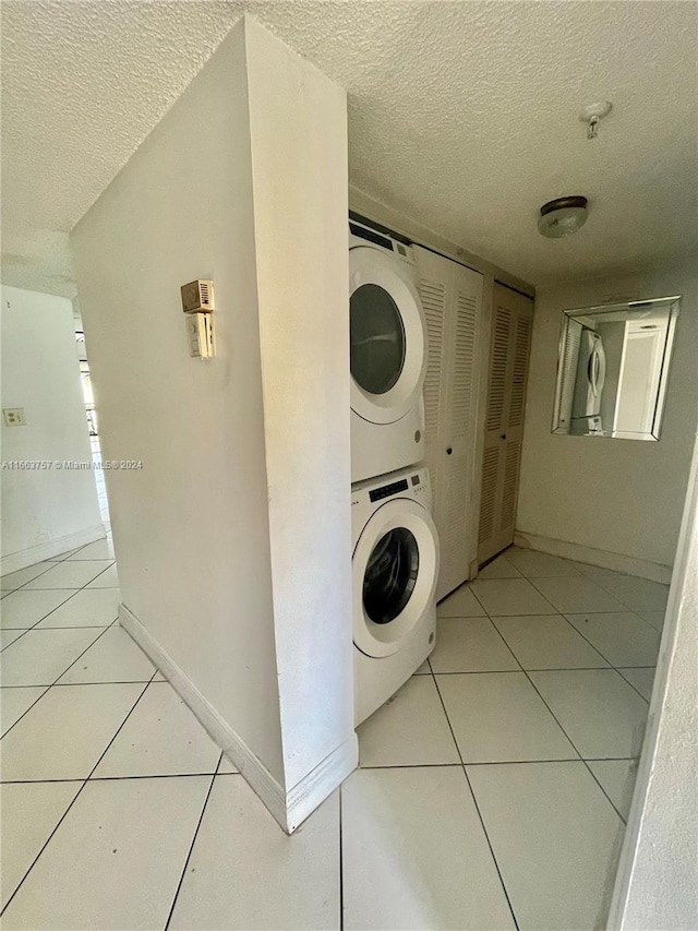 washroom with stacked washer / drying machine, a textured ceiling, and light tile patterned flooring