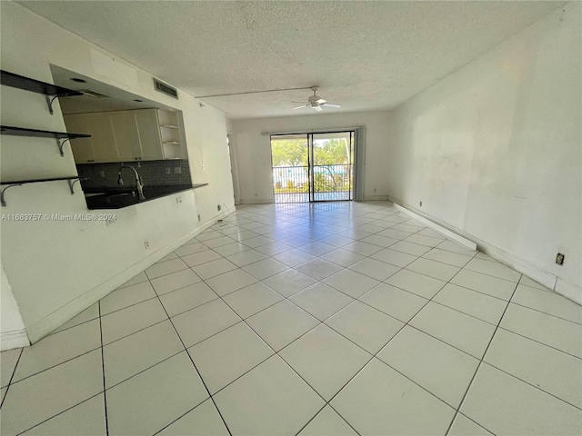 unfurnished living room with ceiling fan, light tile patterned floors, and a textured ceiling