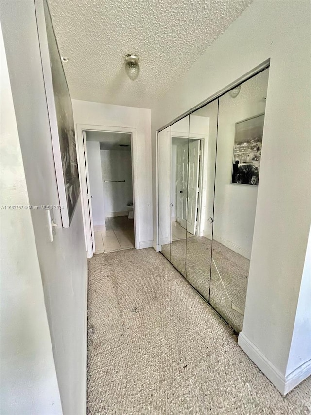 corridor featuring carpet floors and a textured ceiling