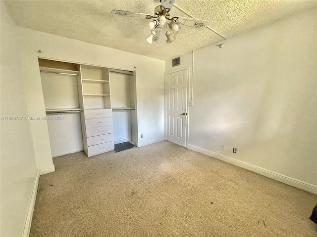 unfurnished bedroom with ceiling fan, a textured ceiling, a closet, and light carpet