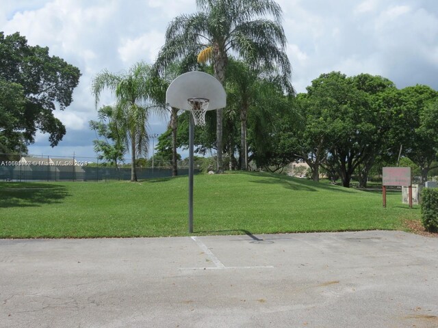 view of community with basketball hoop and a lawn