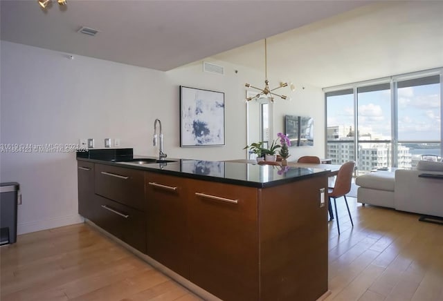 kitchen featuring dark brown cabinets, sink, a chandelier, and light hardwood / wood-style floors