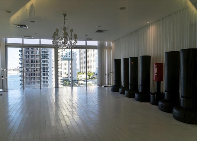 interior space featuring a healthy amount of sunlight, a chandelier, a wall of windows, and hardwood / wood-style floors