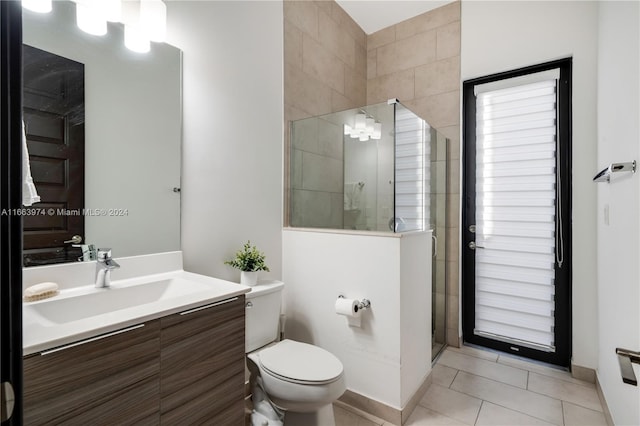 bathroom featuring tile patterned flooring, a shower with door, vanity, and toilet