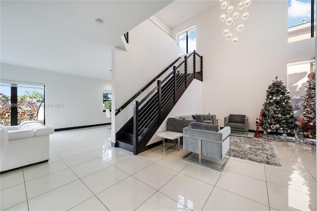 stairs with a towering ceiling, tile patterned floors, and a wealth of natural light