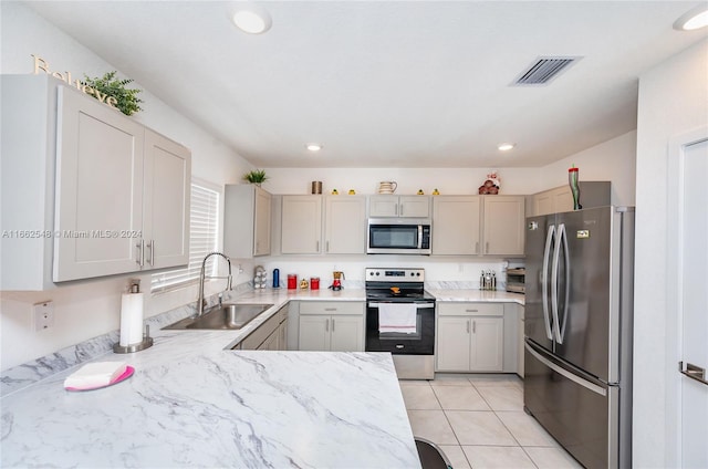 kitchen featuring light tile patterned floors, appliances with stainless steel finishes, sink, and gray cabinetry