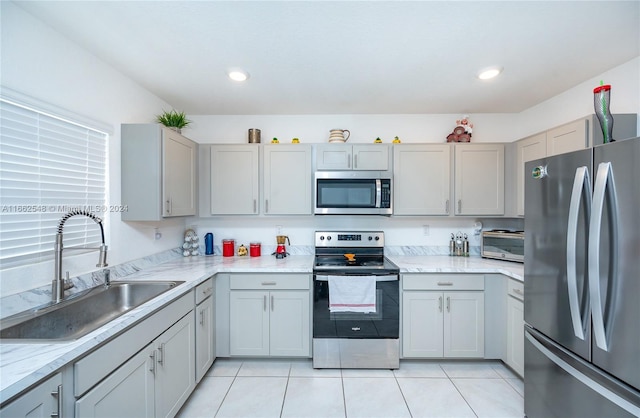 kitchen featuring light stone counters, light tile patterned flooring, sink, gray cabinets, and stainless steel appliances