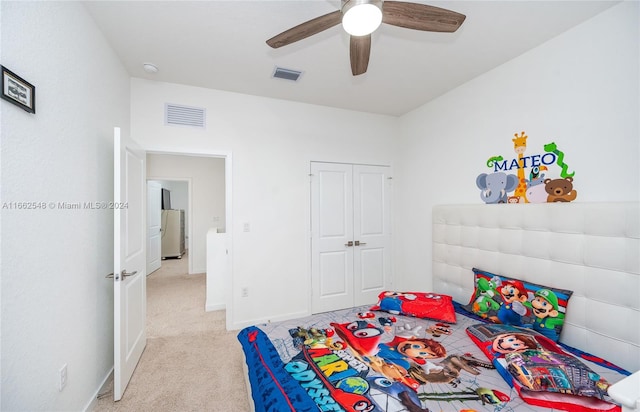 bedroom featuring light carpet, a closet, ceiling fan, and white fridge