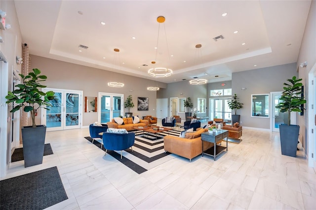 living room with a towering ceiling, a tray ceiling, and french doors