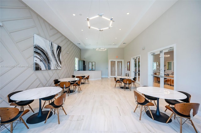 interior space with a notable chandelier, a high ceiling, light hardwood / wood-style flooring, and french doors