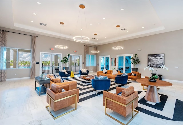 living room with a high ceiling, a tray ceiling, and french doors